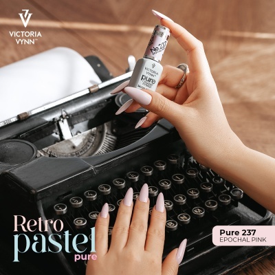 Frasco de verniz de unhas rosa pastel segurado sobre máquina de escrever preta