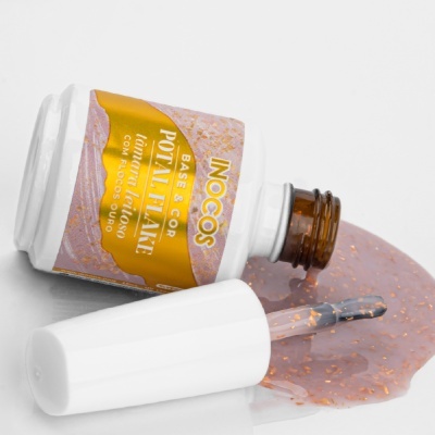 Frasco de verniz para unhas com glitter dourado e tampa branca aberto sobre superfície branca