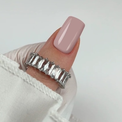 Anel de metal prateado com pedras retangulares em dedo mindinho com unha rosa claro