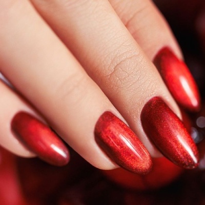 Unhas vermelhas metálicas brilhantes em mão feminina