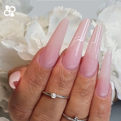Unhas longas rosa com detalhes brancos e anéis prateados, mãos femininas com flores brancas ao fundo