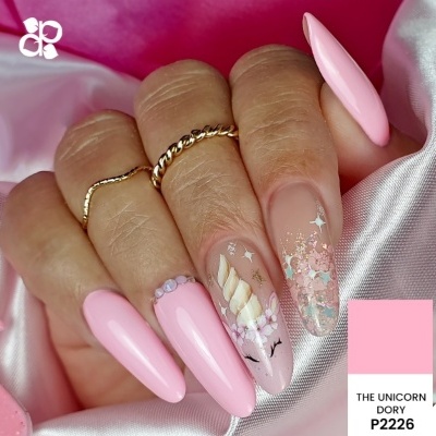 Unhas cor-de-rosa com decoração de unicórnio e detalhes brilhantes em fundo de cetim rosa