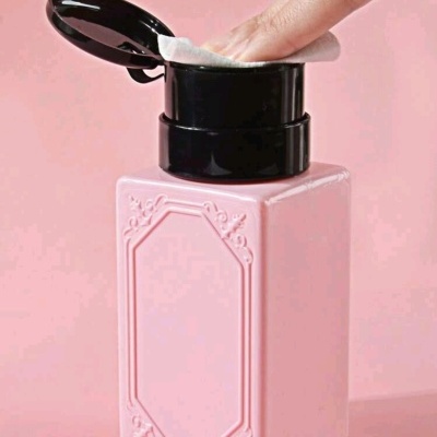 Frasco quadrado rosa com tampa preta contendo discos de algodão.