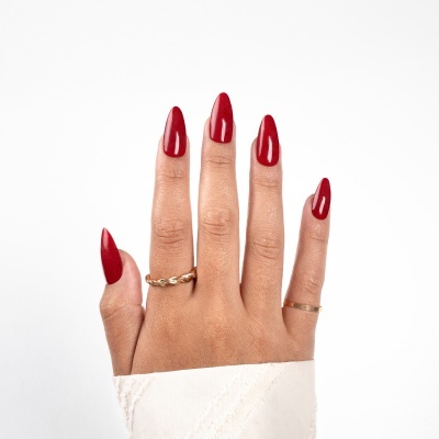 Mão com unhas vermelhas e anéis dourados