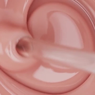 Close-up mostrando a textura cremosa rosa de um produto de maquilhagem a ser misturado