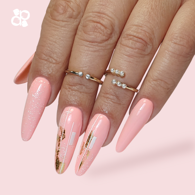 Mãos femininas com unhas stiletto rosa com detalhes dourados e anéis de pérolas