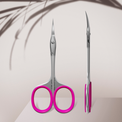 Tesouras pequenas em metal com encaixes rosa sobre superfície clara
