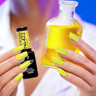 Unhas pintadas com verniz amarelo segurando frasco de verniz e frasco de vidro com líquido amarelo