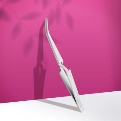 Pinça metálica prateada com ponta curvada sobre superfície branca e fundo rosa