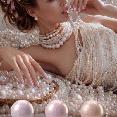 Mulher com muitas joias de pérolas e unhas pintadas com gel polish cor pérola clara