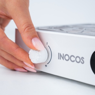 Mão a rodar botão de dispositivo branco com marca INOCOS