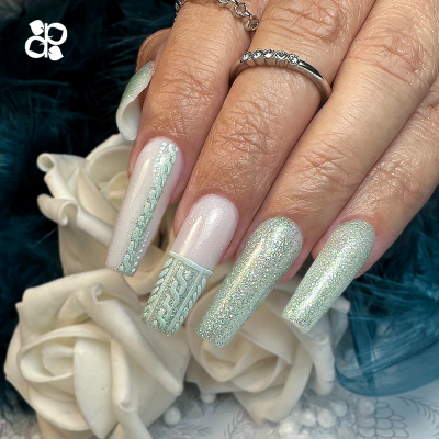 Unhas longas verde claro e prateado com detalhes em trança, flores brancas e fundo azul escuro.