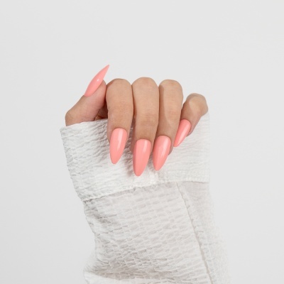 Mão feminina com unhas compridas cor de rosa seguro tecido branco