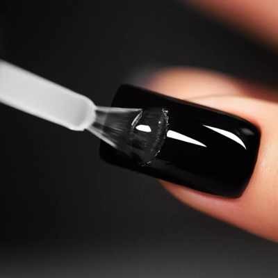 Aplicação de verniz transparente numa unha pintada de preto