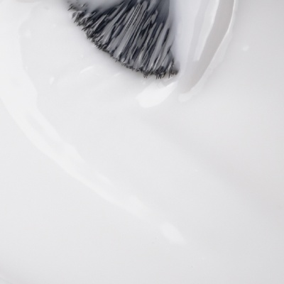 Pincel preto com esmalte branco aplicado numa superfície branca