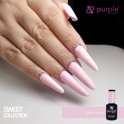 Mão com unhas longas rosa claro decoradas com cristais e frascos de verniz gel