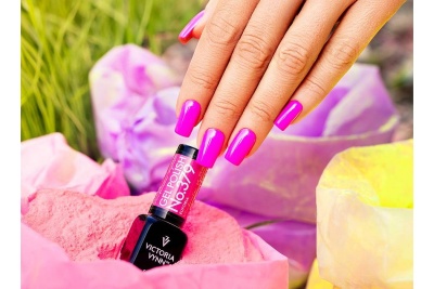 Frasco de verniz gel rosa Victoria Vynn com mão feminina e pó colorido