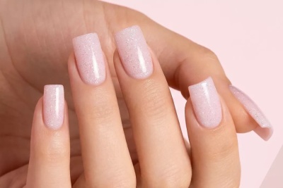 Unhas artificiais quadradas rosa claro com glitter prateado em mãos femininas