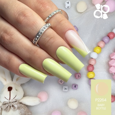 Unhas compridas com verniz verde e nude com ponta branca, anéis prateados e brinquedos de peluche ao fundo