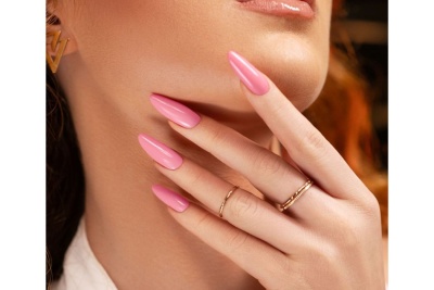 Mãos femininas com unhas rosa e anéis dourados