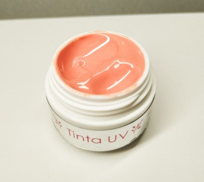 Frasco aberto com creme cor de salmão etiquetado Tinta UV