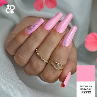 unhas artificiais rosa com detalhes metálicos e anéis dourados na mão