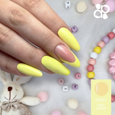 Unhas femininas amarelas com textura e decoração negative space em fundo com contas e coelho de pelúcia