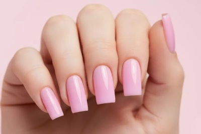 Unhas longas quadradas com verniz rosa claro brilhante em fundo rosa