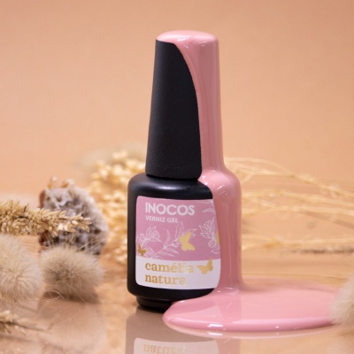 Frasco preto de verniz gel Inocos rosa com verniz derramado e flores secas ao fundo