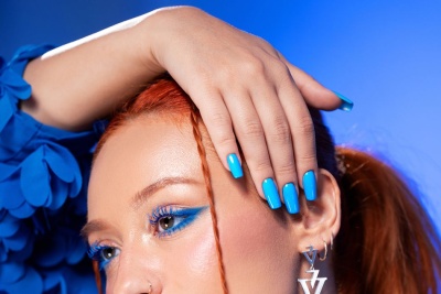 Pessoa com maquilhagem azul, cabelo ruivo e unhas azuis