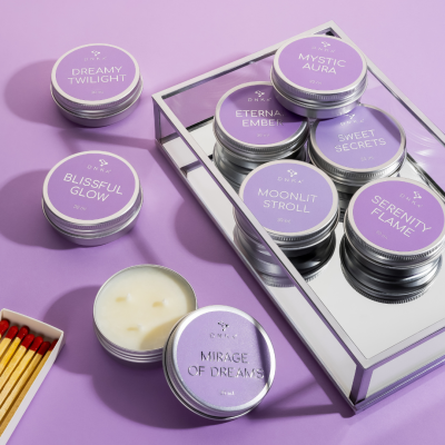 velas em latas metálicas roxas com nomes diferentes dispostas sobre fundo lilás