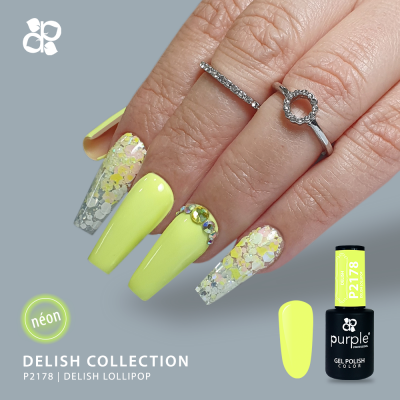 Unhas com verniz gel amarelo néon e decoração com glitter e pedras, e anéis prateados com brilhantes.