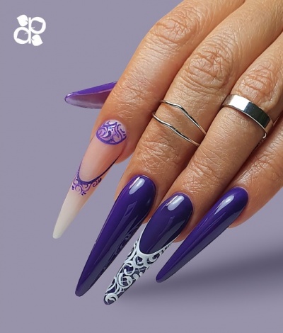 Unhas compridas decoradas com verniz roxo e desenhos brancos e roxos, anéis prateados, fundo roxo