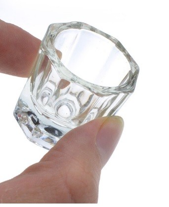 Copo de vidro pequeno e transparente segurado pela mão