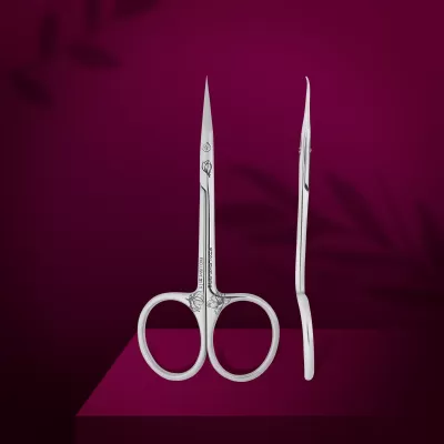 Tesouras de manicure em metal prateado com detalhes gravados sobre fundo roxo