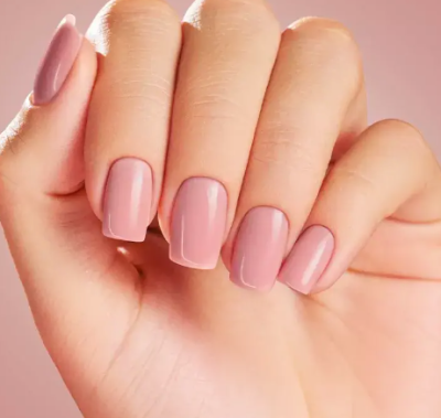 Mão com unhas em gel rosa claro brilhantes