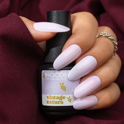 Mão segurando verniz INOCOS vintage natura com unhas rosas longas