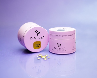 Frasco cor-de-rosa DNKA Gold Gel com cápsulas amarelas sobre superfície lilás