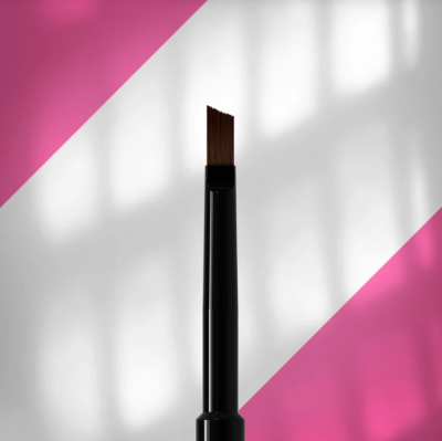 Pincel de maquilhagem preto e castanho sobre fundo branco e rosa