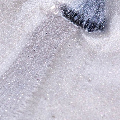 Pincel com verniz brilhante prateado sobre superfície granulada