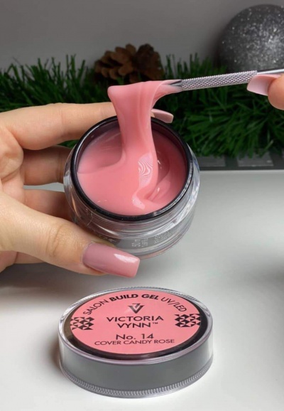 Gel para unhas rosa Victoria Vynn num frasco aberto com tampa ao lado e espátula a retirar o gel.