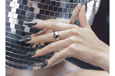 Mão com unhas pretas brilhantes e anel prateado segurando máscara prateada de espelhos.