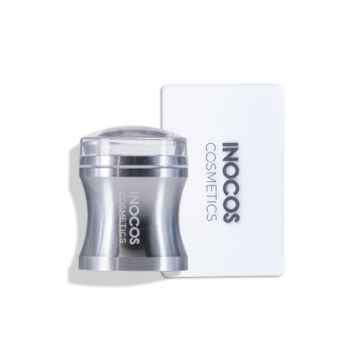 Depilador corporal prateado com tampa transparente ao lado de cartão branco com texto INOCOS COSMETICS