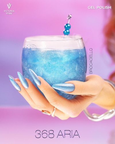 Mão com unhas azuis cintilantes segurando copo com líquido azul