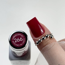 Frasco de verniz vermelho escuro com texto, mão com unha pintada e anel prateado