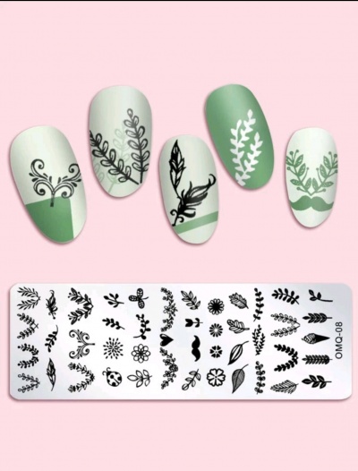 Unhas postiças com desenhos de folhagem e placa metálica com padrões decorativos pretos.