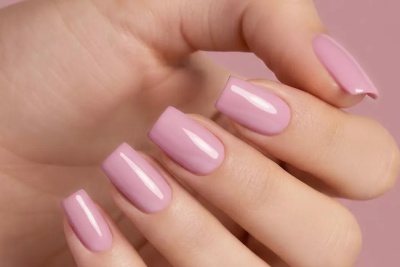 Unhas quadradas pintadas de verniz rosa claro em fundo rosa
