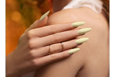 Mão com unhas verdes longas e anéis dourados com pérola sobre ombro