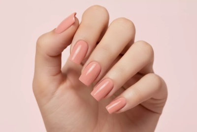Unhas compridas pintadas de verniz cor de pêssego brilhante