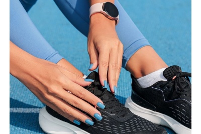 Ténis desportivos pretos com sola branca usados numa superfície azul